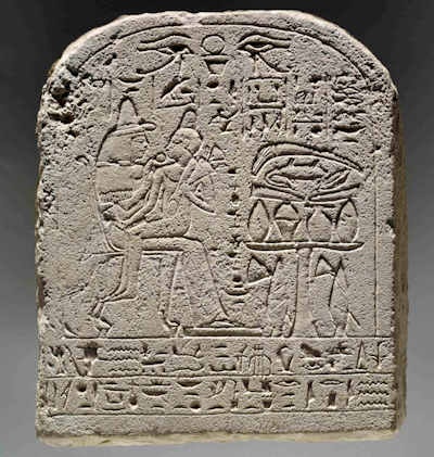 Round-topped limestone stela of Merysekhmet depicting the deceased child seated on the lap of his mother. 18th Dynasty.