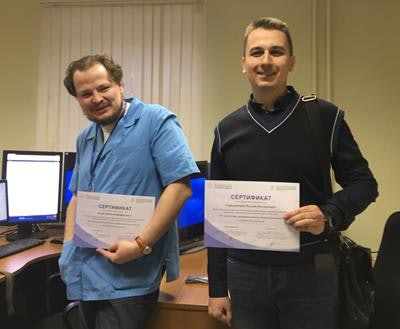 Two candidates proudly display their certificates at the end of the training process.