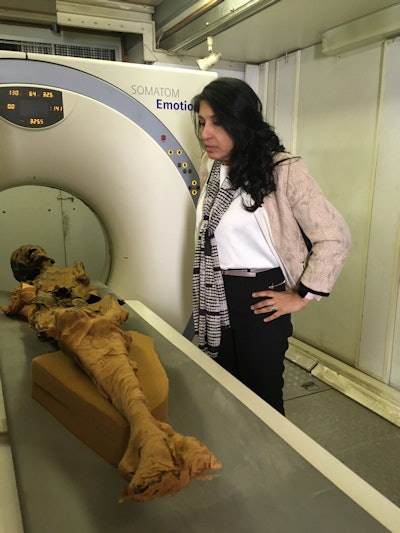 Dr. Sahar Saleem looks closely at the mummy on the CT scanner table.