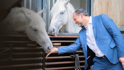 Prof. Michael Fuchsjäger, ESR chair of the board of directors, feeding the Lipizzaner stallions at the Spanish Riding School in Vienna. The school puts on horsemanship performances, with the riders in traditional cavalry dress, and these shows are a popular attraction in Vienna. Photo courtesy of the ESR.