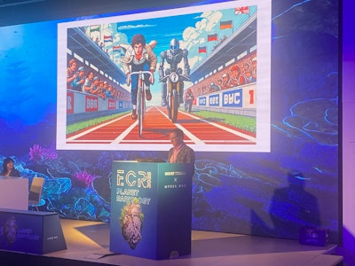 Dr. Marc Kohli discusses current and potential future uses of generative AI in radiology at ECR 2025 in Vienna, Austria. Behind him is an image created by one such generative AI model, which illustrates humans working alongside AI.