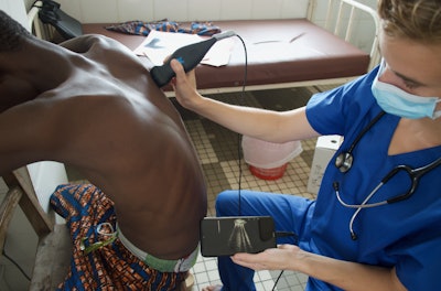 Véronique Suttels, PhD, performs an ultrasound scan on a patient in Benin, West Africa, using a POCUS scanner connected to a smartphone. Her team studied how an AI-guided POCUS system can help diagnose tuberculosis in patients with respiratory symptoms. Image courtesy of Véronique Suttels, PhD.