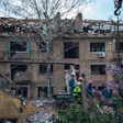 Firefighters in Kyiv inspect a damaged building after an attack, illustrating the destruction wrought by the war.