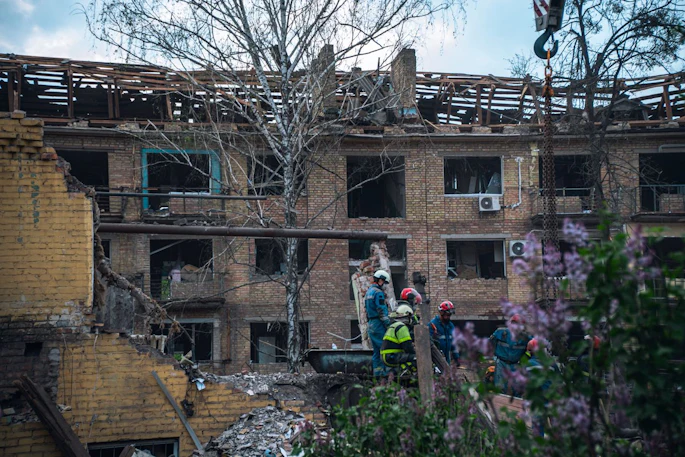 Firefighters in Kyiv inspect a damaged building after an attack, illustrating the destruction wrought by the war.