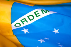 Brazilian flag waving with green, yellow, and blue colors and white band displaying 'ORDEM' text