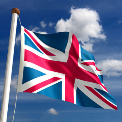 Union Jack flag waving on a flagpole against a bright blue sky with white clouds