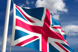 Union Jack flag waving on a flagpole against a bright blue sky with white clouds
