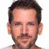 Professional headshot of a man with dark hair and facial hair against a white background