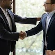 Two businessmen in suits shaking hands during a professional meeting