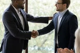 Two businessmen in suits shaking hands during a professional meeting