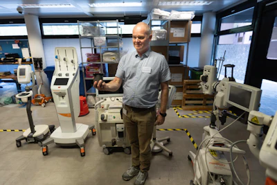 Medical professional standing in laboratory surrounded by diagnostic equipment and monitoring devices