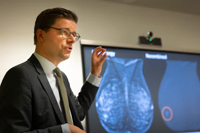 Professional man in glasses presenting mammogram imaging data on a medical display screen during a presentation