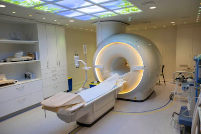 Modern MRI scanner room with illuminated machine, white cabinetry, and patient bed in medical facility