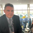 Professional man in dark suit at medical conference with Ultravist product display in background
