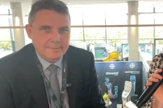 Professional man in dark suit at medical conference with Ultravist product display in background