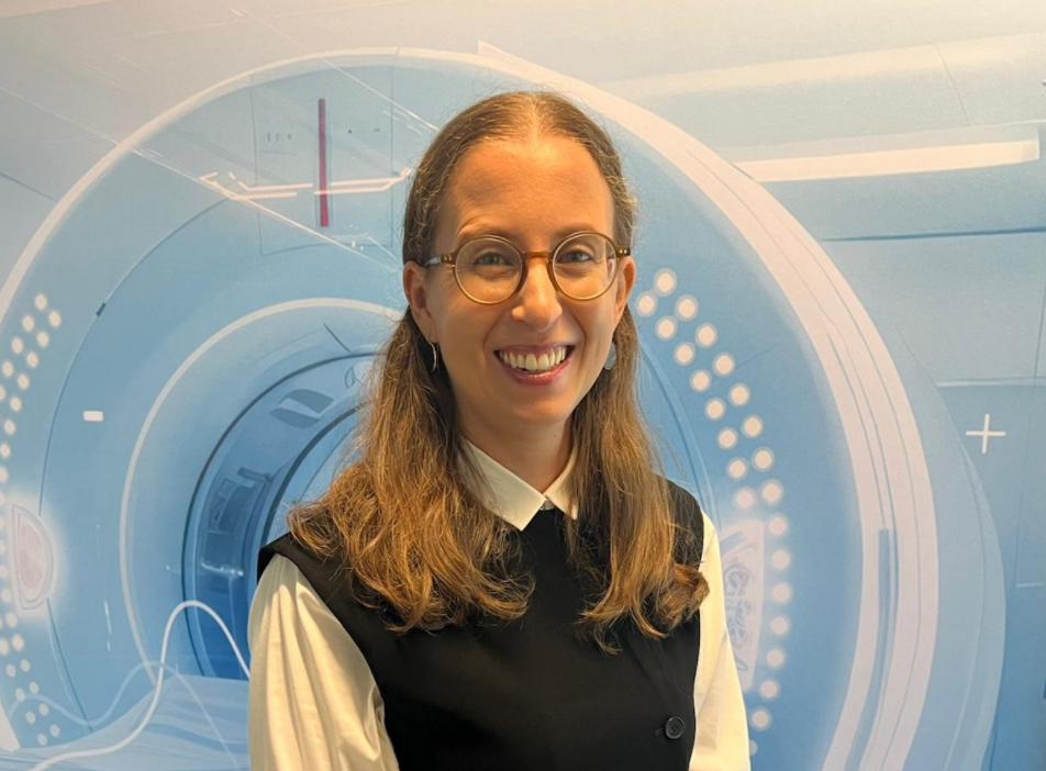 Smiling woman with glasses wearing professional black and white attire in front of futuristic blue circular design