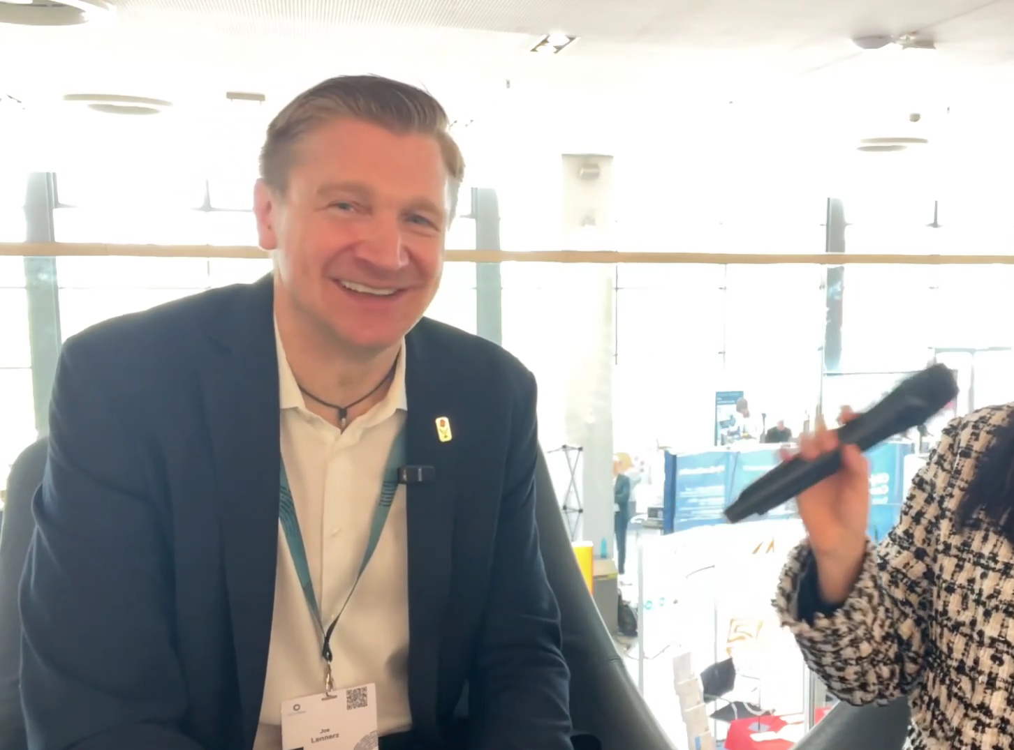 Professional man in navy blazer smiling at conference event wearing ID badge