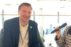 Professional man in navy blazer smiling at conference event wearing ID badge