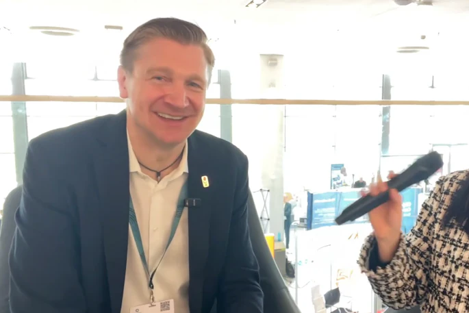Professional man in navy blazer smiling at conference event wearing ID badge
