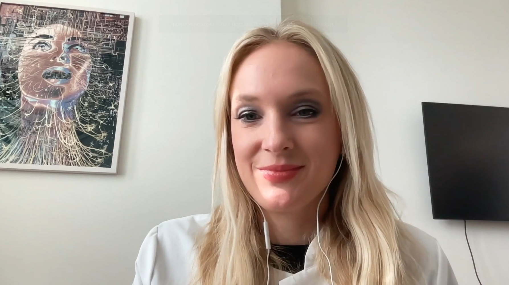 Woman with blonde hair wearing white shirt smiling at camera in office setting