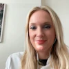 Woman with blonde hair wearing white shirt smiling at camera in office setting