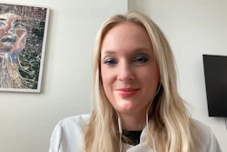 Woman with blonde hair wearing white shirt smiling at camera in office setting