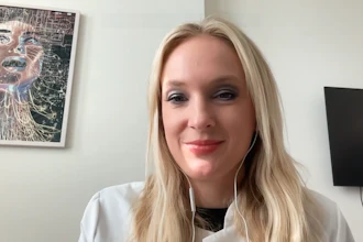 Woman with blonde hair wearing white shirt smiling at camera in office setting