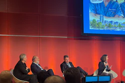 Panel discussion with four business professionals seated on stage against red LED backdrop at conference event