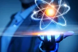 Hand holding glowing atom symbol with blue and gold light effects against blurred tech background
