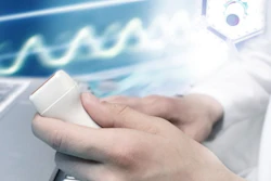 Hand holding white technology device with digital waveforms and data visualization in background