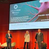 Three speakers presenting at NEURORAD 2026 conference in Mainz, with neurological imagery displayed on screen behind them