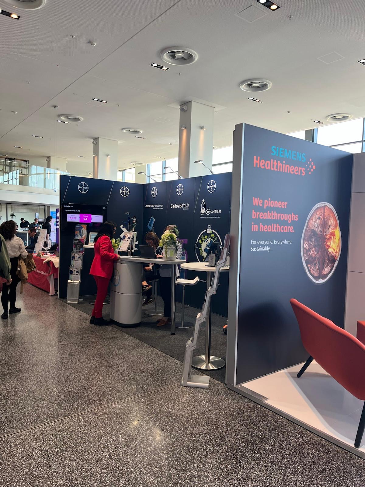 Siemens Healthineers exhibition booth at trade show with navy blue signage displaying company logo and healthcare messaging