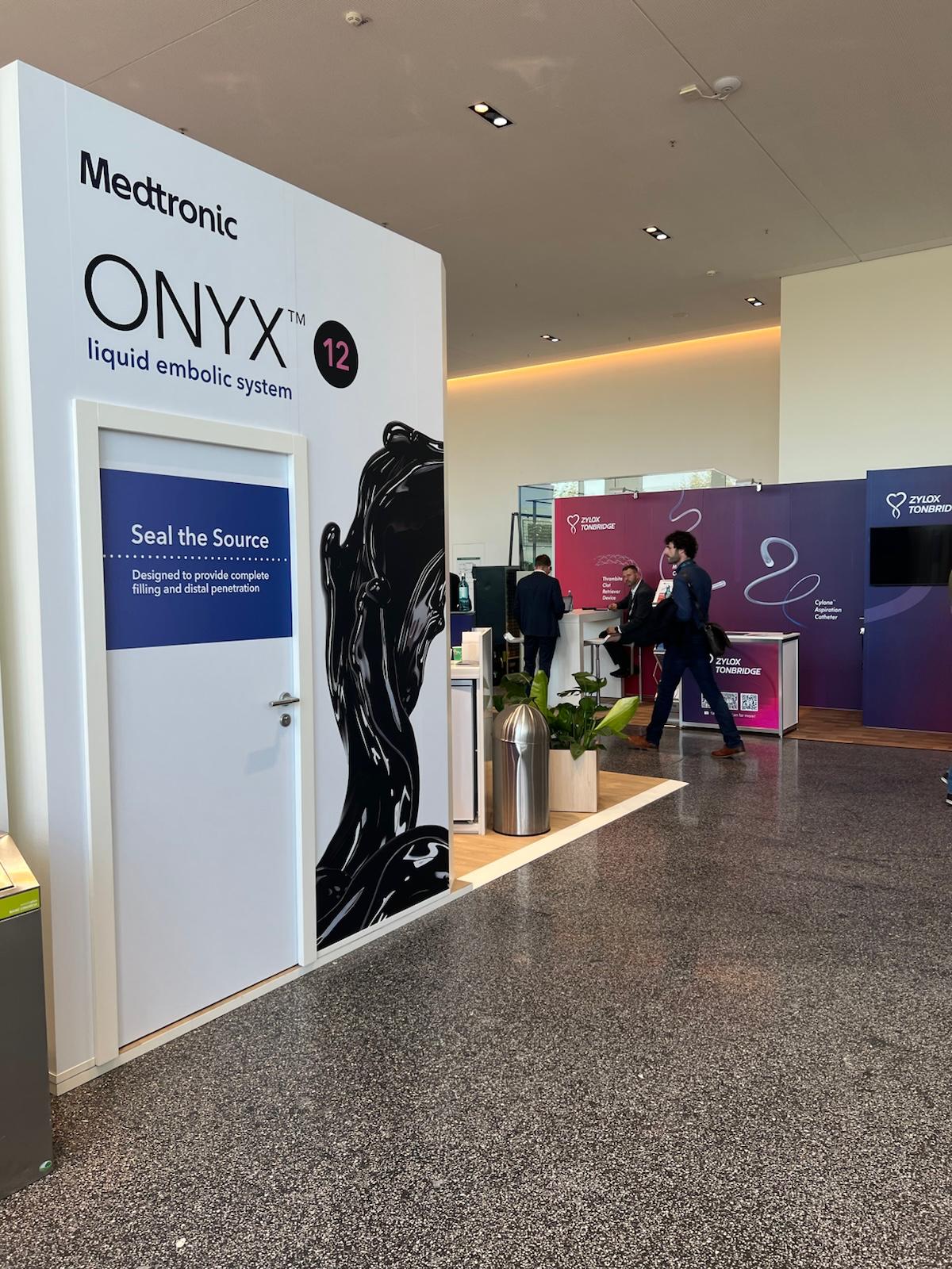 Medtronic ONYX liquid embolic system booth at medical trade show with promotional signage and visitors