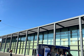 Modern glass building facade with metal framework and parked blue information vehicle under clear blue sky