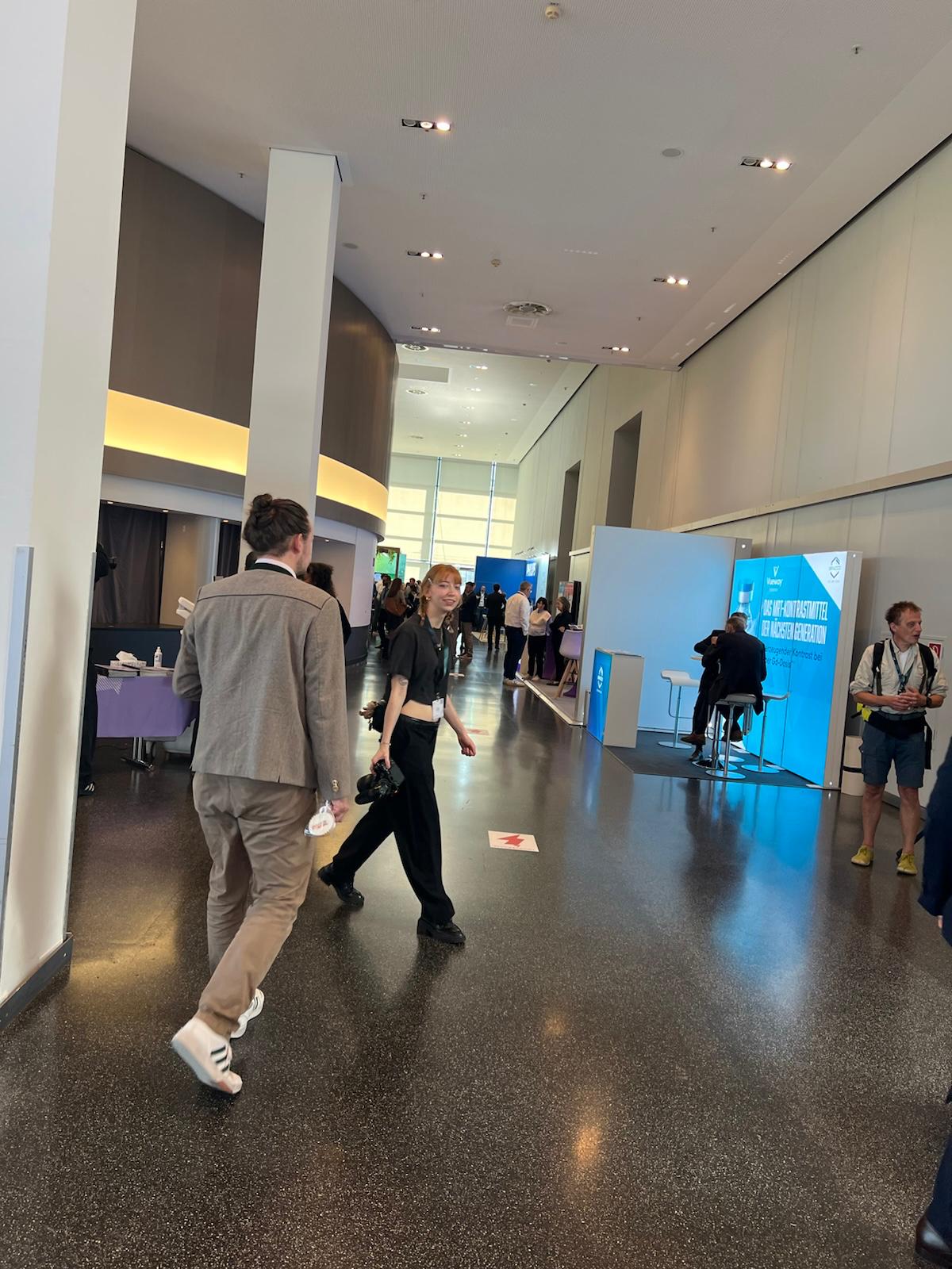 Modern convention center lobby with attendees walking past blue exhibition signage and white architectural columns