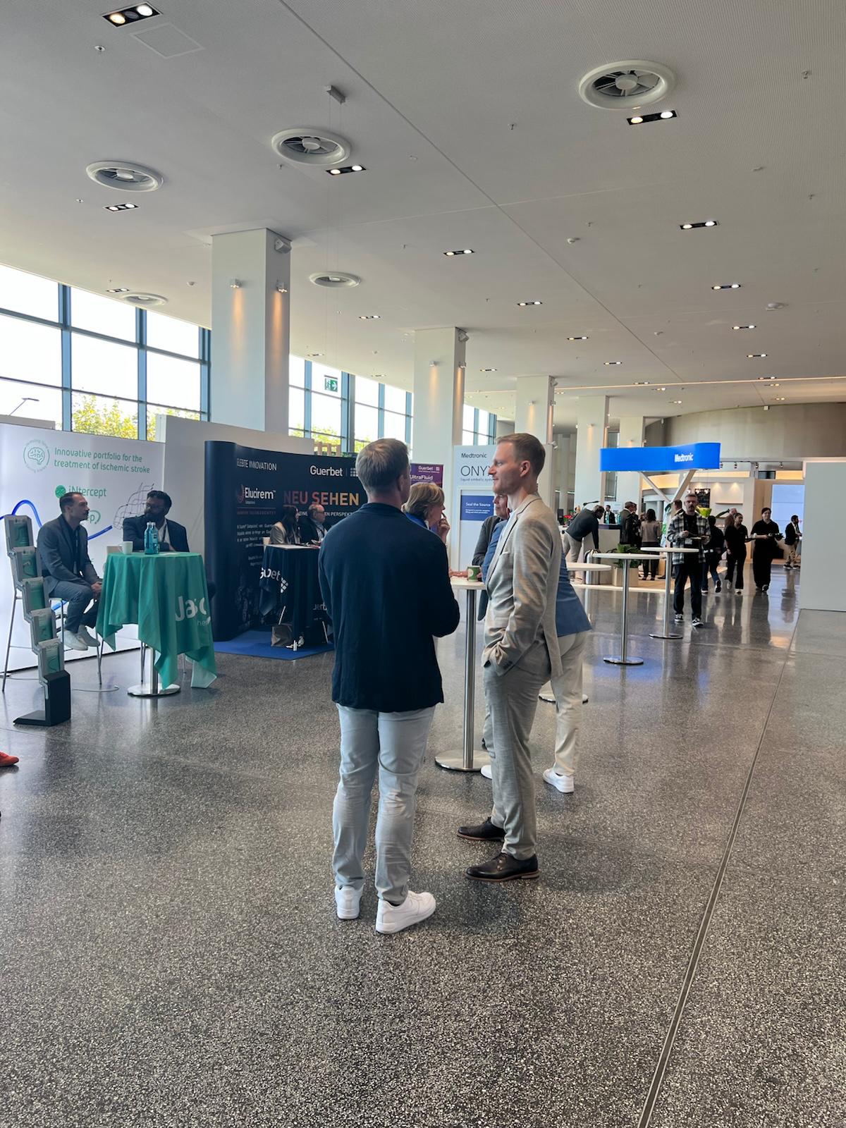 Professional networking event in modern convention center with attendees visiting branded exhibition booths