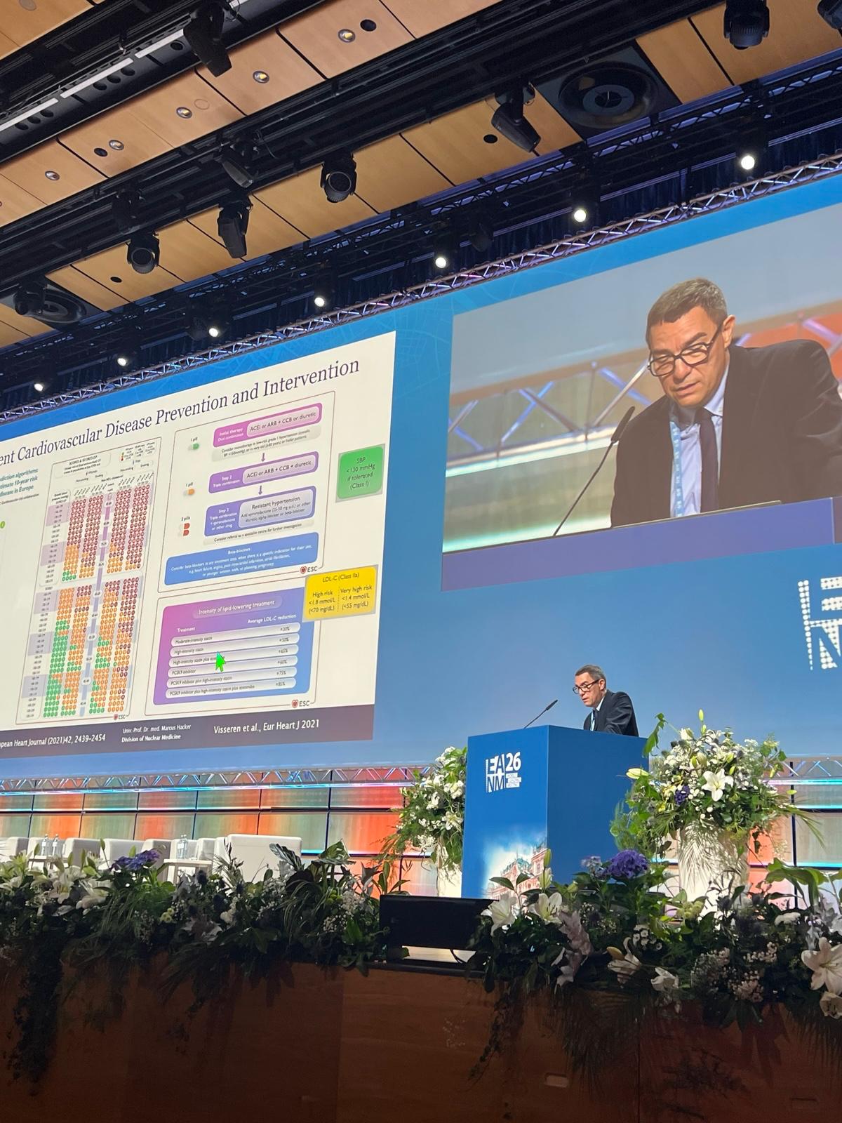 Medical professional presenting cardiovascular disease prevention research at conference with data visualization on large screen display