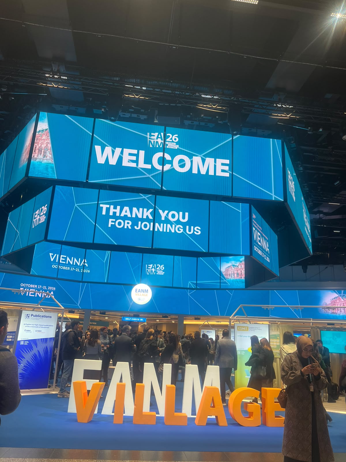 EAM26 Vienna conference venue with blue geometric welcome signage and orange 'VIENNAGE' branding at indoor event space