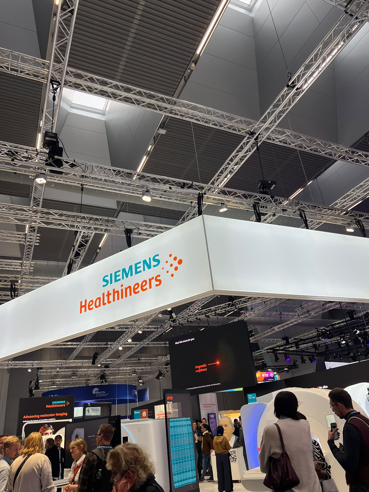 Siemens Healthineers trade show booth with white signage and orange branding in industrial exhibition hall