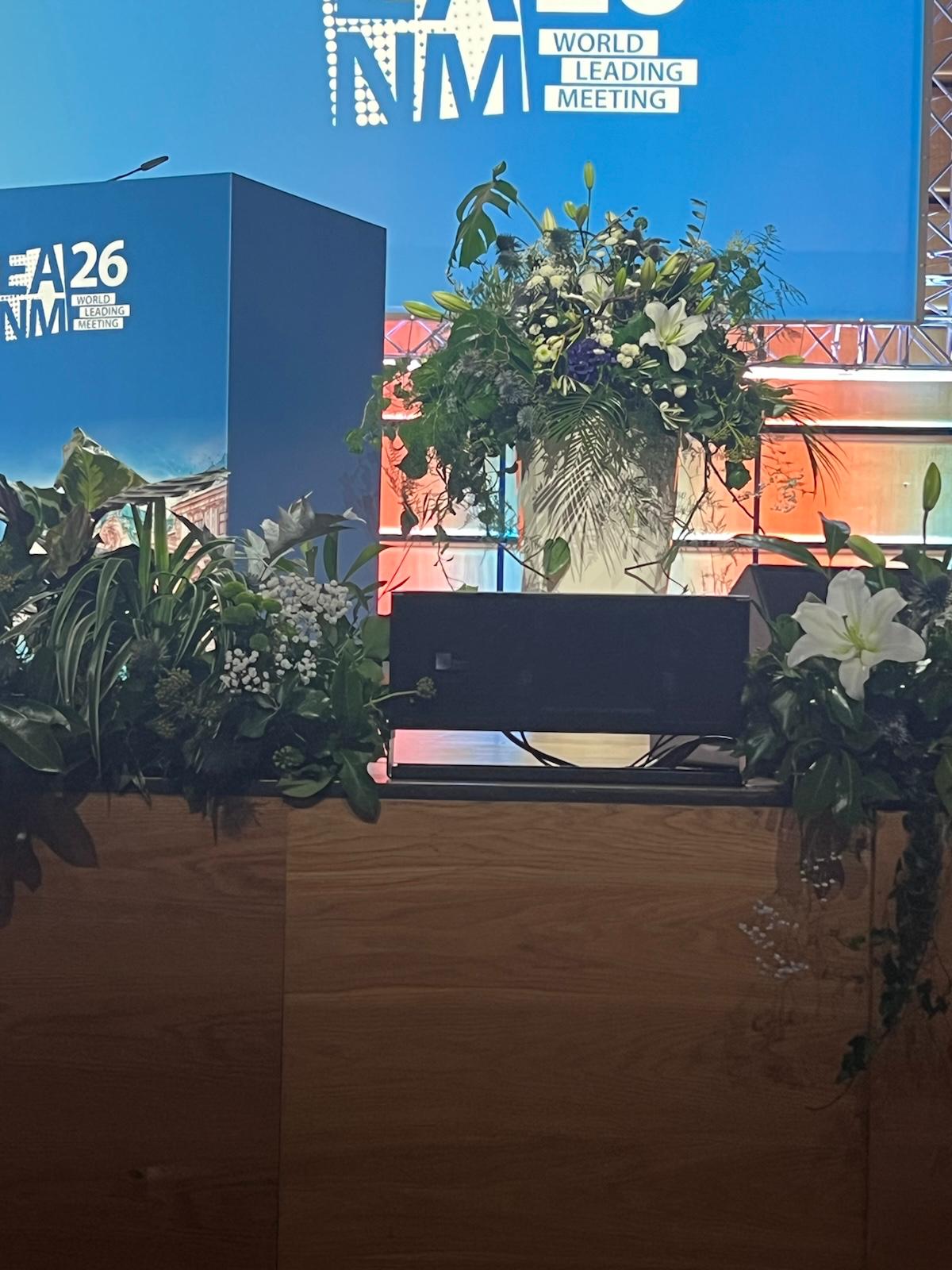 NMA World Leading Meeting event venue signage with decorative plants and flowers at FA26 conference